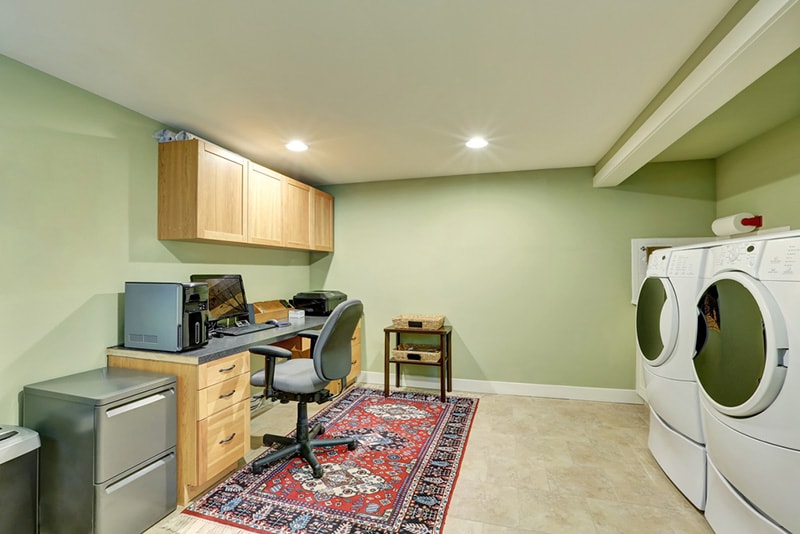Basement room with combination of home office area and laundry appliances