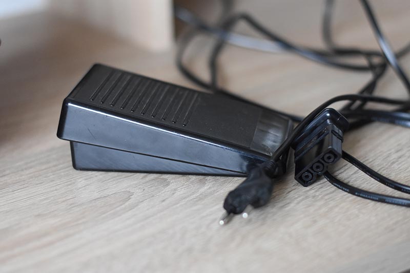 Black plastic control pedal and electric plug of sewing machine