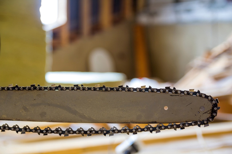 close up view of a chainsaw bar and cutting chain at construction site