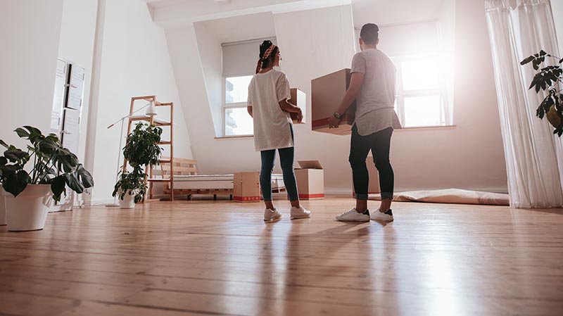 couple holding boxes and moving in new house