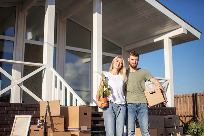 Couple Standing on steps on new Home with moving cardboard boxes