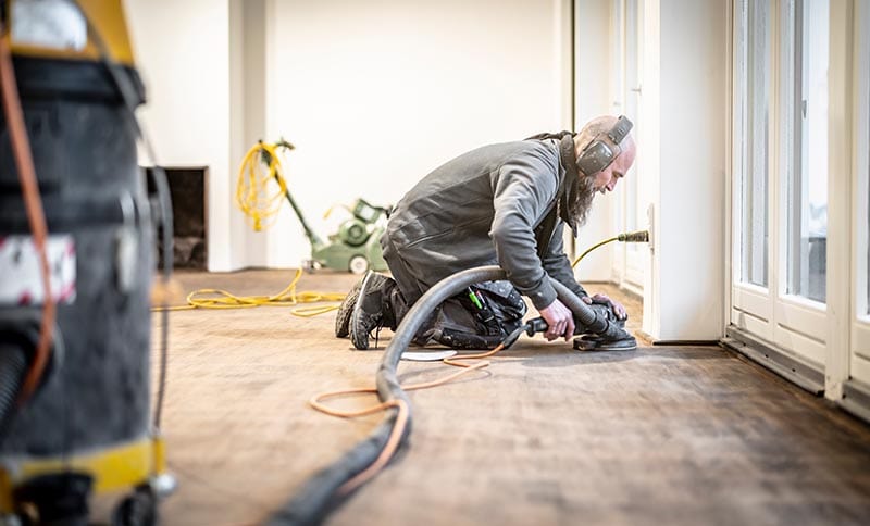 Craftsman grinds the parquet floor with the edge grinder