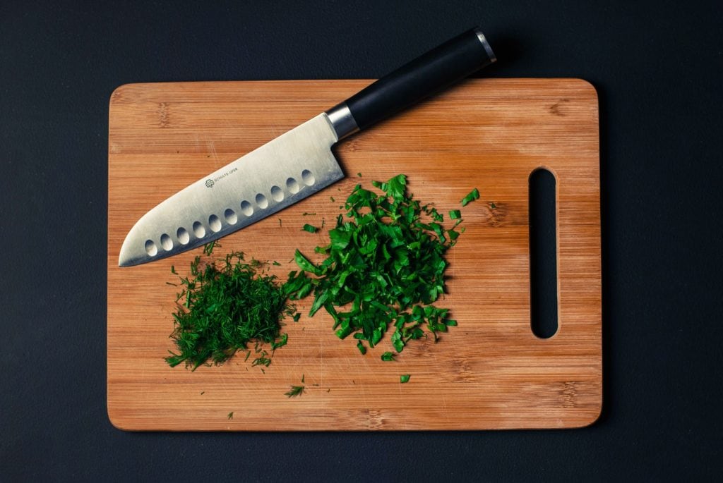Chopping board with knife and herbs
