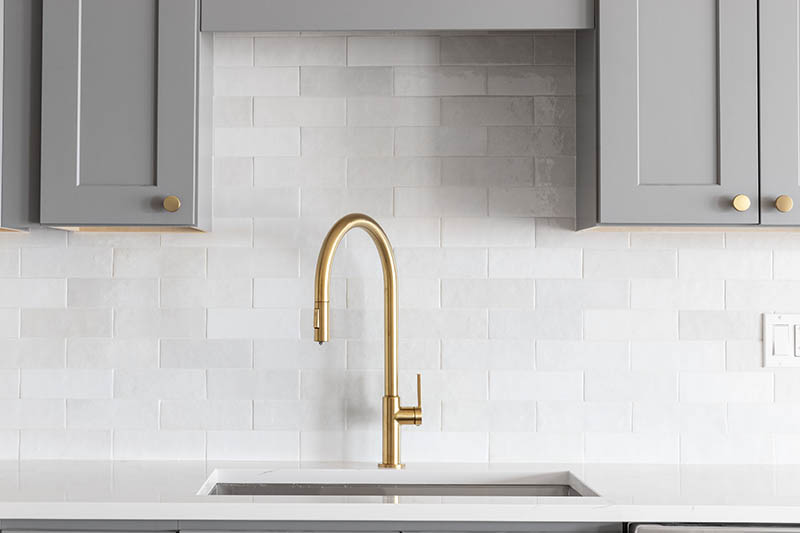 kitchen sink with gold faucet and gray kitchen cabinet