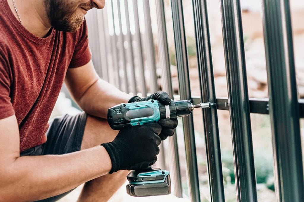 man drilling metal fence