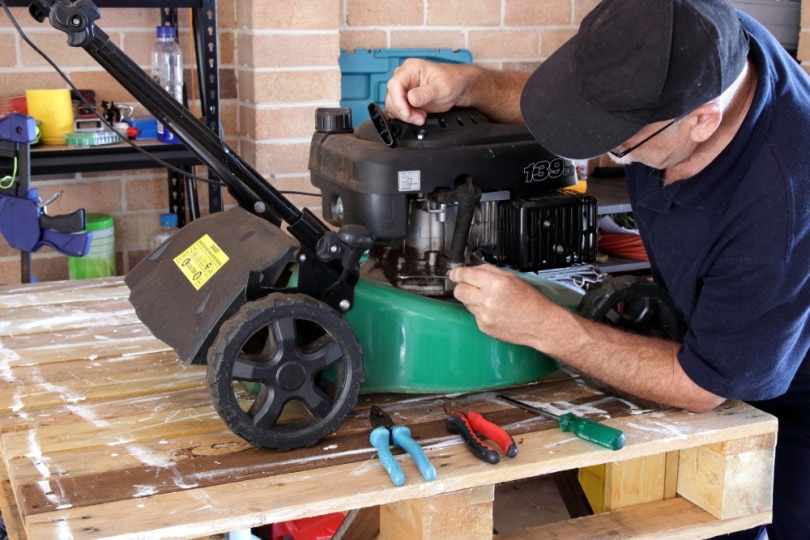 man fixing lawn mower engine