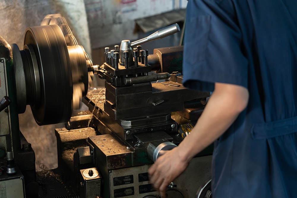 Man operating lathe grinding machine