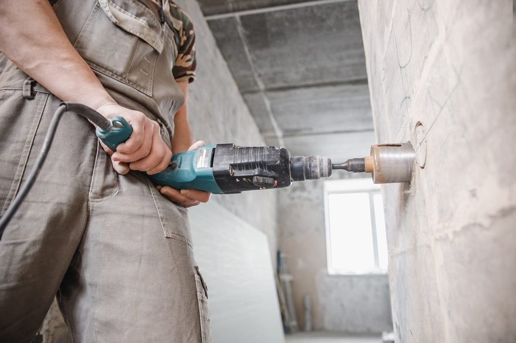 man using hammer drill on concrete