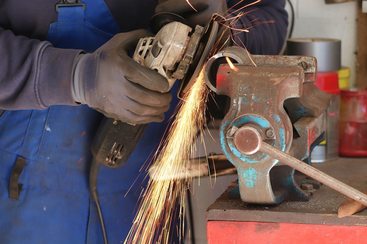 man working on a metal piece with an angle grinder