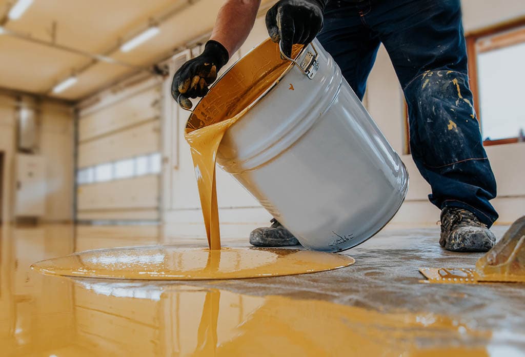 person applying yellow epoxy on the floor