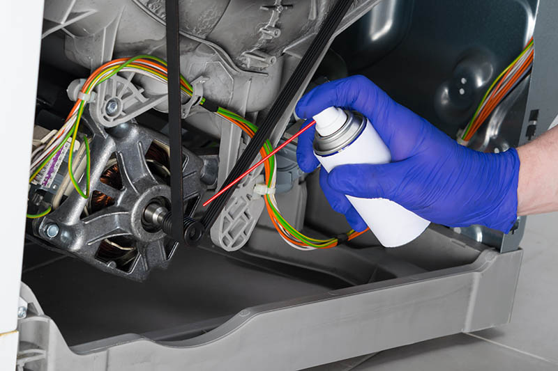 person cleaning machine parts using WD-40