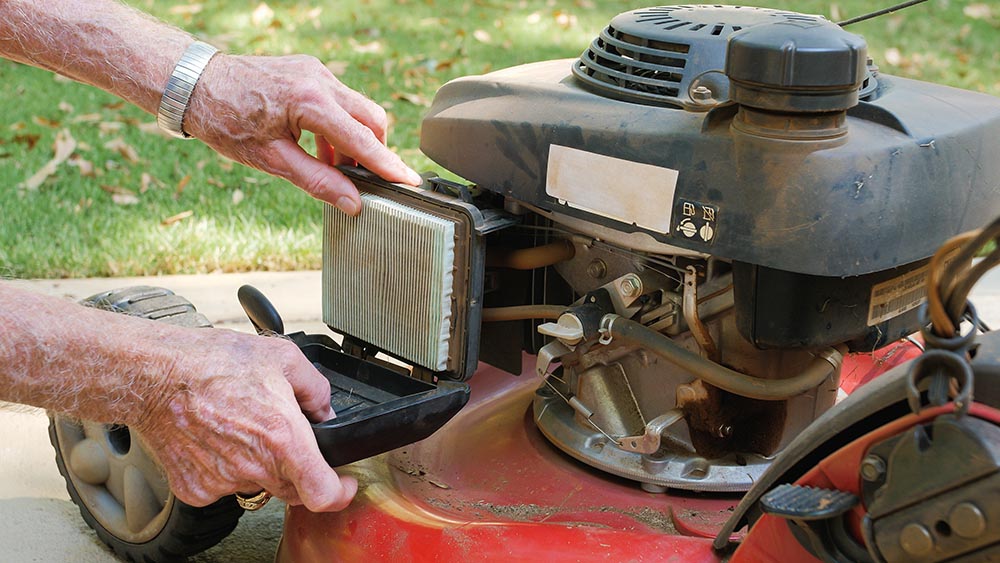 person replacing air filter of lawnmower