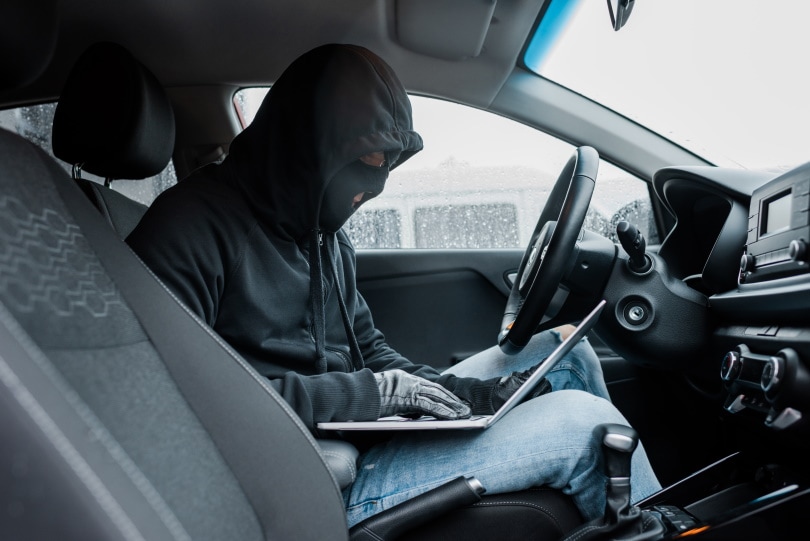 robber holding laptop inside car