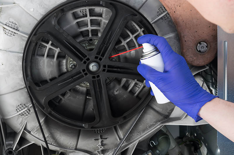 spraying WD-40 on machine part