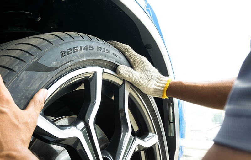 Tire Size numbers and Tyre Load Indexes on the sidewall on blurred hand of Auto mechanic on background