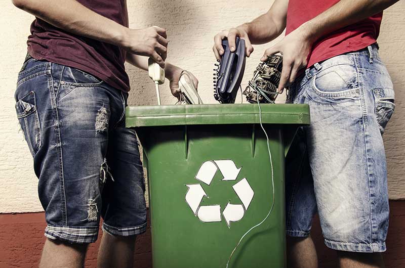 Two man putting electronic waste into recycle bin