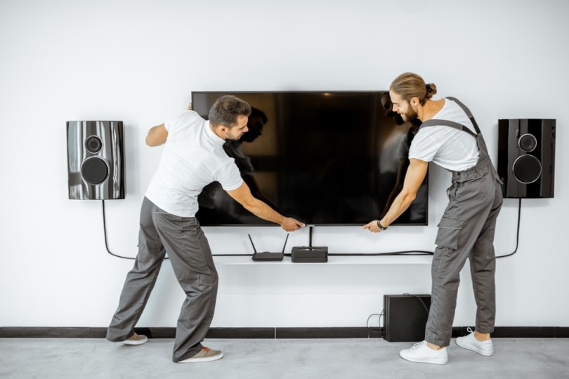 two men installing TV on wall