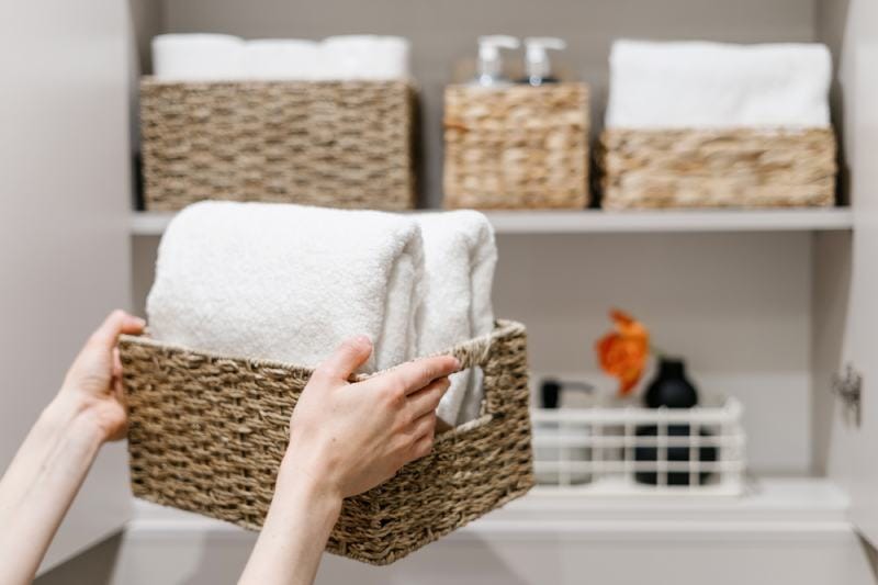 Wicker basket with Clean fresh towels neatly folded and placed in closet organizer box
