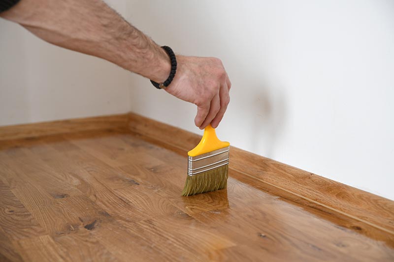 Worker uses a brush to coating floors